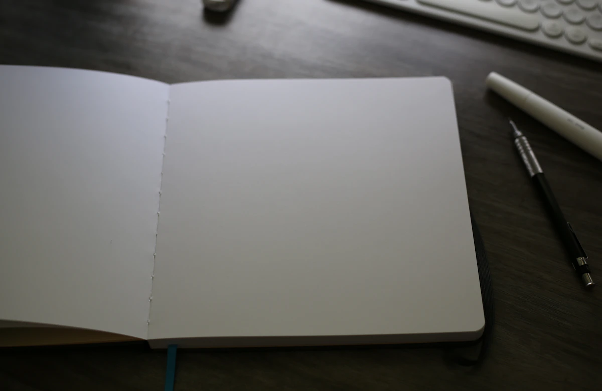 An open sketchbook and pencils beside a keyboard